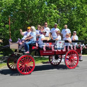 American Comrades and friends riding a carriage for a parade.